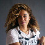 Carri Twigg - Black woman, swept up hair, white shirt