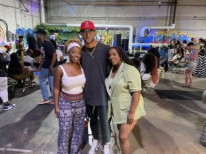 A man and two women stand close smiling at camera