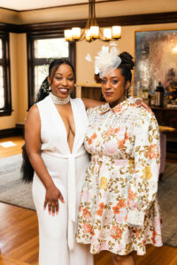 Two elegantly dressed women, one with a fascinator in her hair.