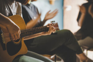 Three people singing with a guitar in the foreground.